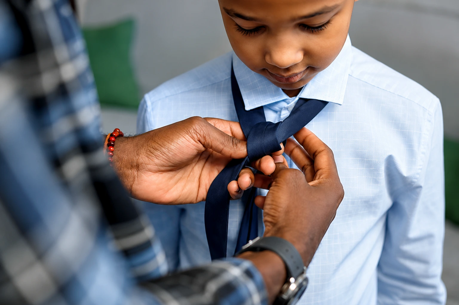 A parent helping a young child tie his tie, illustrating why teaching manners early sets children up for lifelong success.