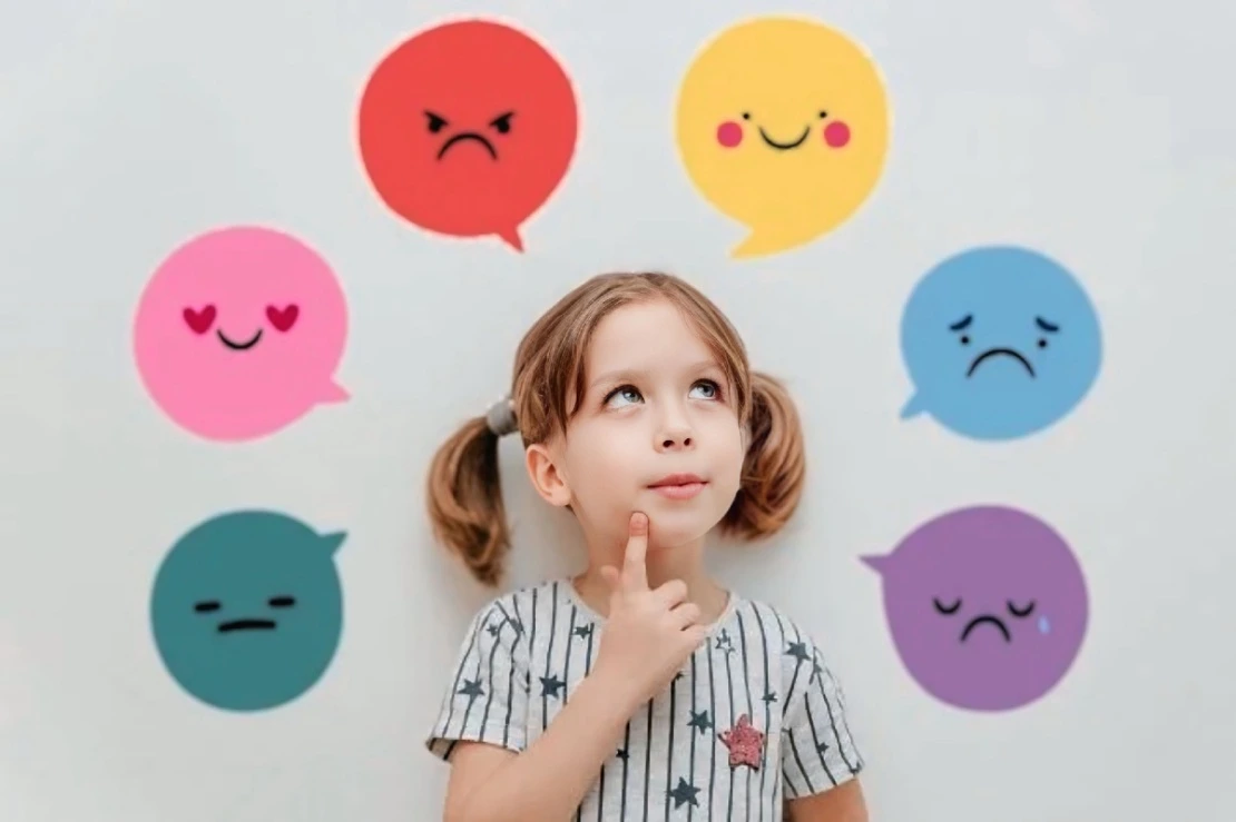 A thoughtful young girl with pigtails looking up at colorful speech bubbles floating above her head, illustrating effective tips on how to build emotional intelligence in children.